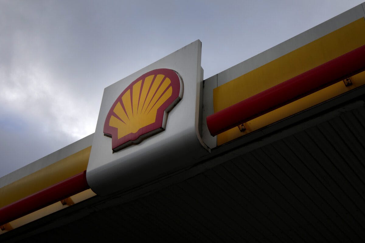 Shell-logo på fasaden til en bensinstasjon mot en overskyet himmel.
