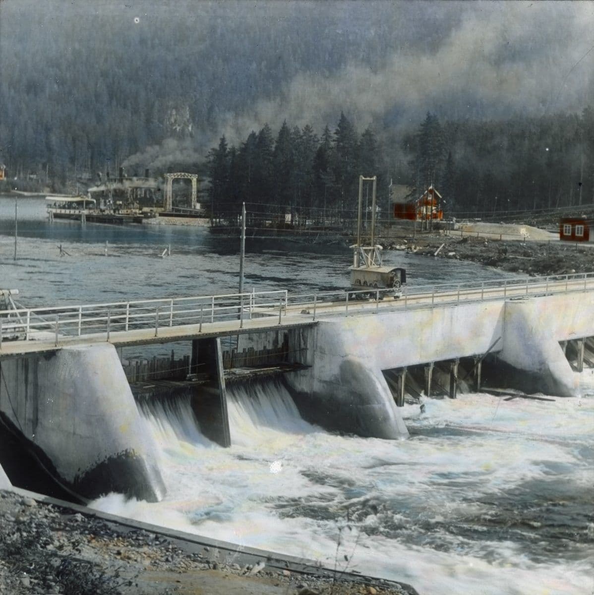 Fotografen Anders Beer Wilse var og opptatt av krafteventyret. Her har han fanga inn demningsanlegget i Tinnsjå, og kalt Tinnsjøen, i 1910. I bakgrunnen Tinnsjåferga. Bildet er håndkolorert.