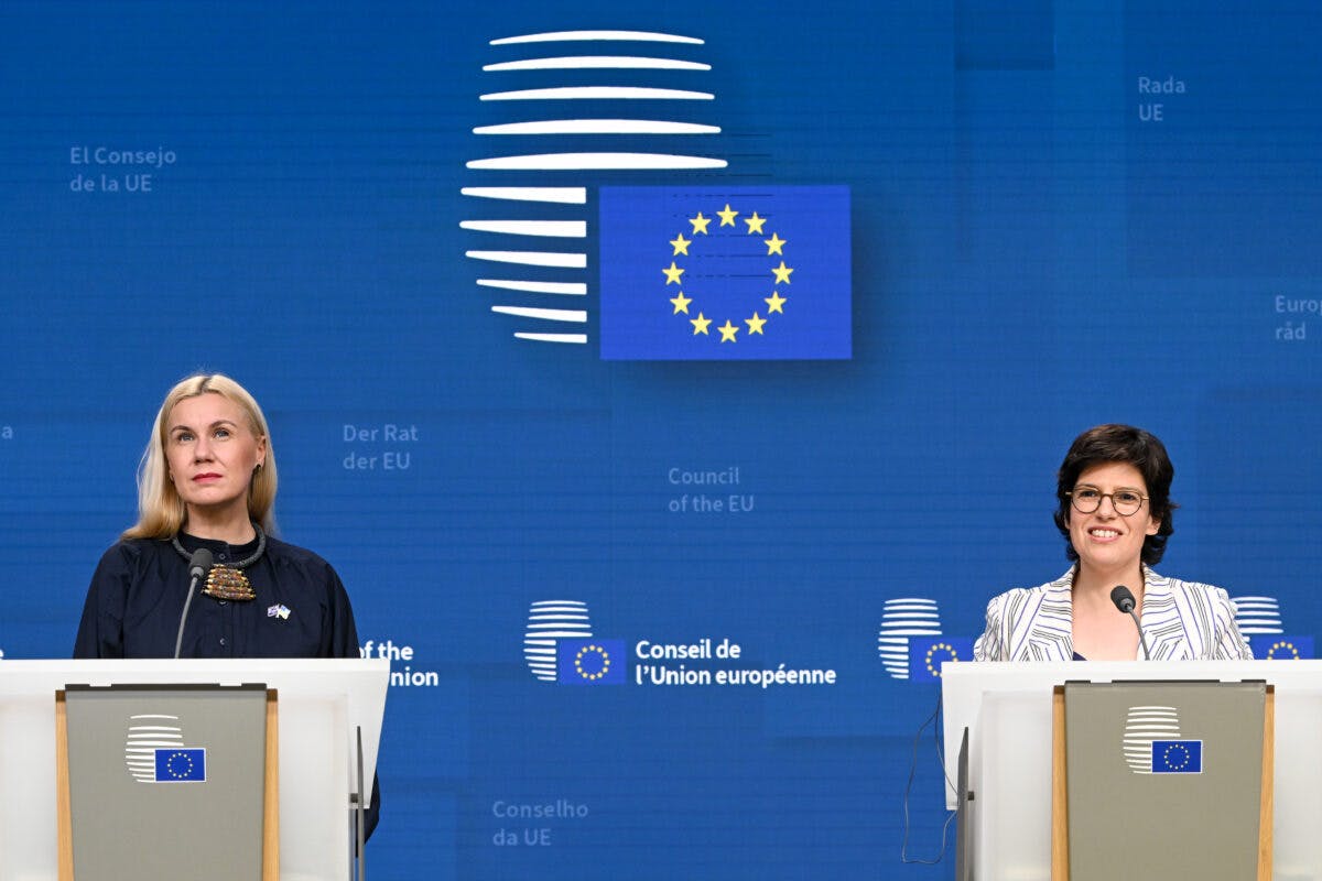 To kvinner står ved podier med EU-emblemet bak seg, og henvender seg til media i EUs råd.