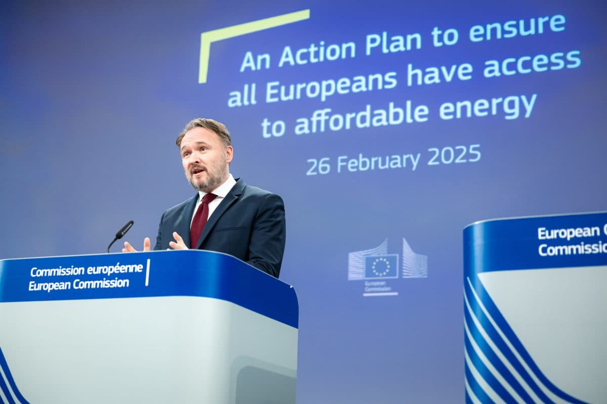 En mann taler ved et podium merket «European Commission» med et presentasjonslysbilde om en handlingsplan for rimelig energi datert 26. februar 2025, i bakgrunnen.