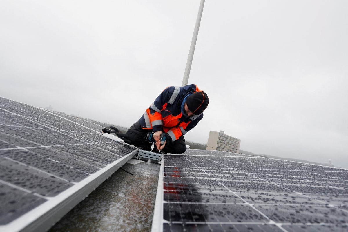 mann monterer solcellepaneler på tak