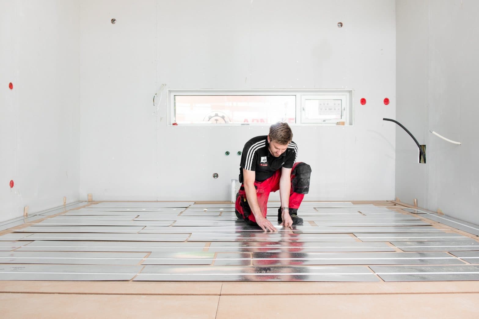 Mann legger gulvvarme i bolig