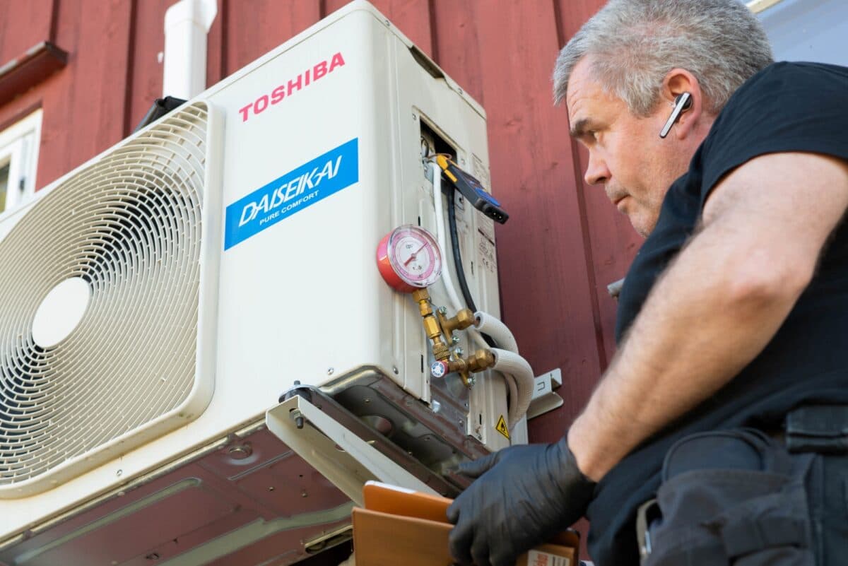 Montør måler gasstrykk på varmepumpe.