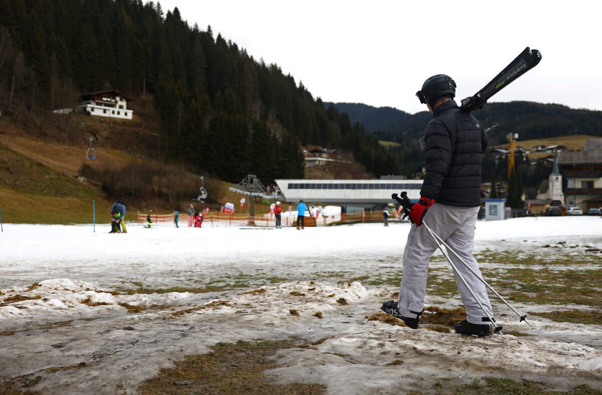 Skiers pass on a small layer of an artificial snow in Filzmoos