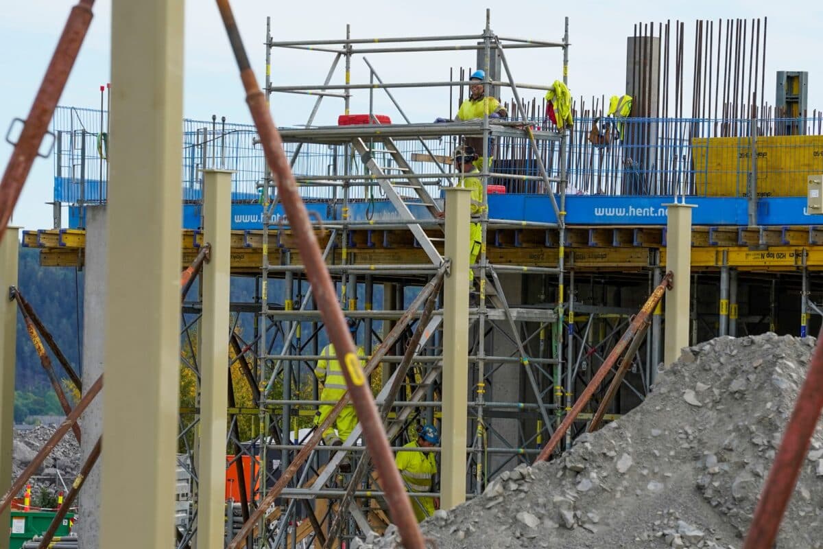 Byggearbeidere på byggeplass, stillaser.