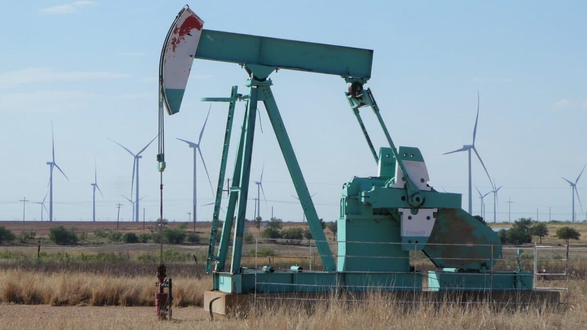 Oljerigg med vindmøller i bakgrunnen.