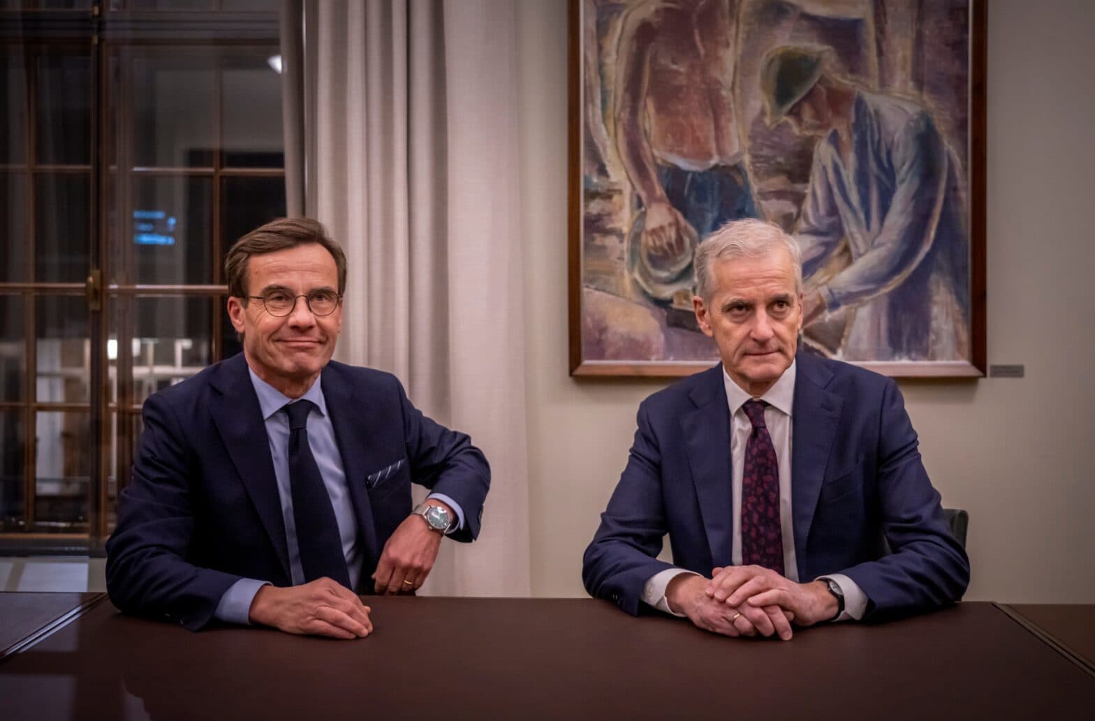 Kristersson og Støre bak skrivebord.