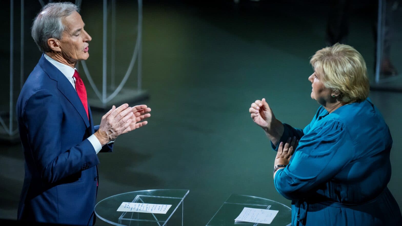 En kvinne i en blå kjole snakker med en mann i dress.