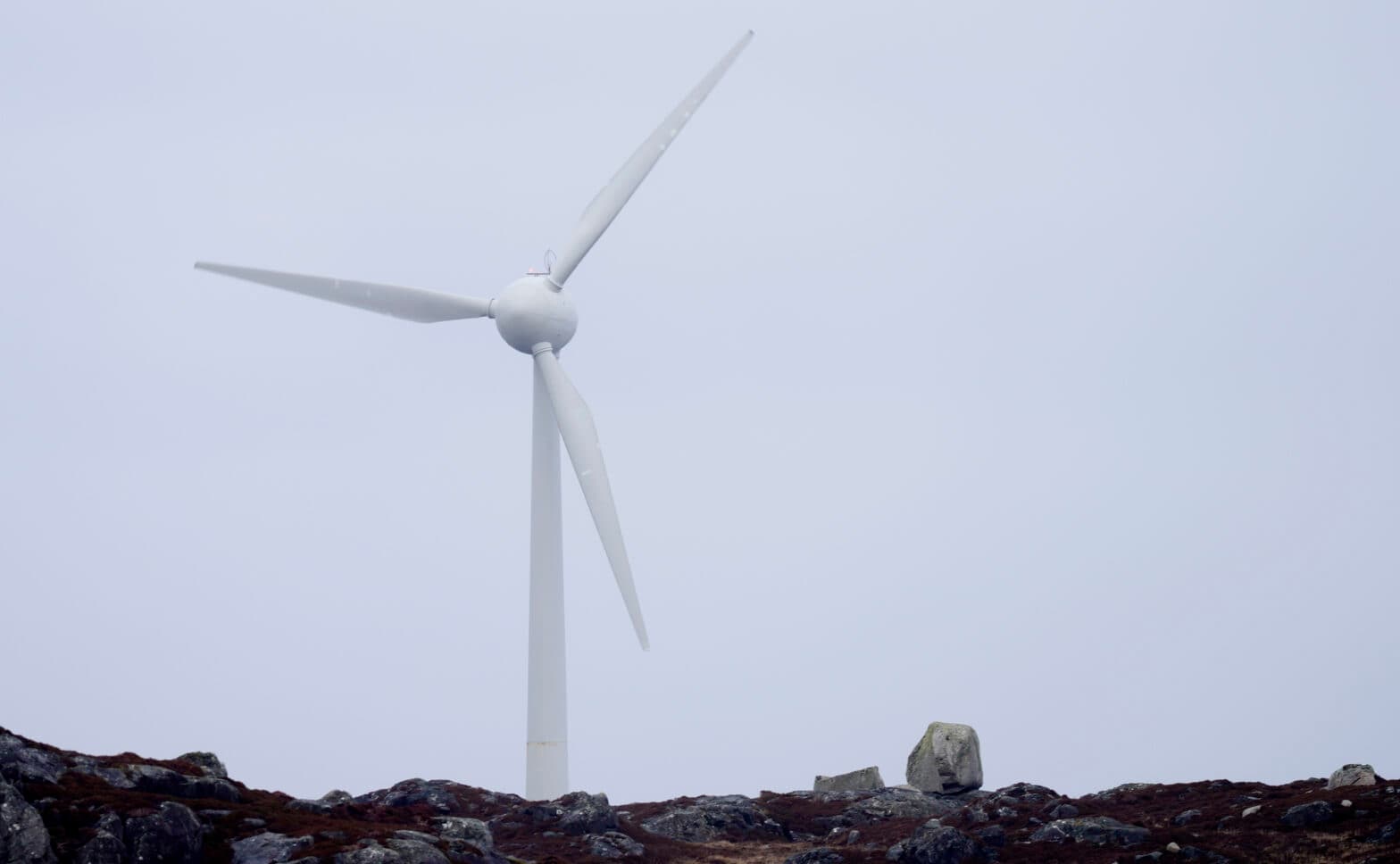 En vindturbin sitter på toppen av en steinete bakke.