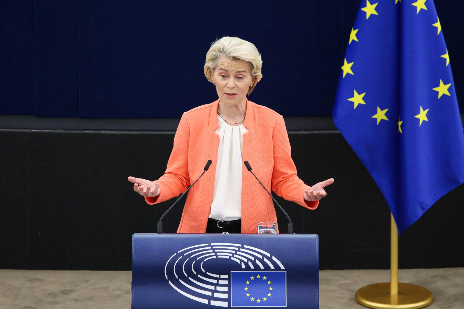 En kvinne som står på et podium foran et eu-flagg.