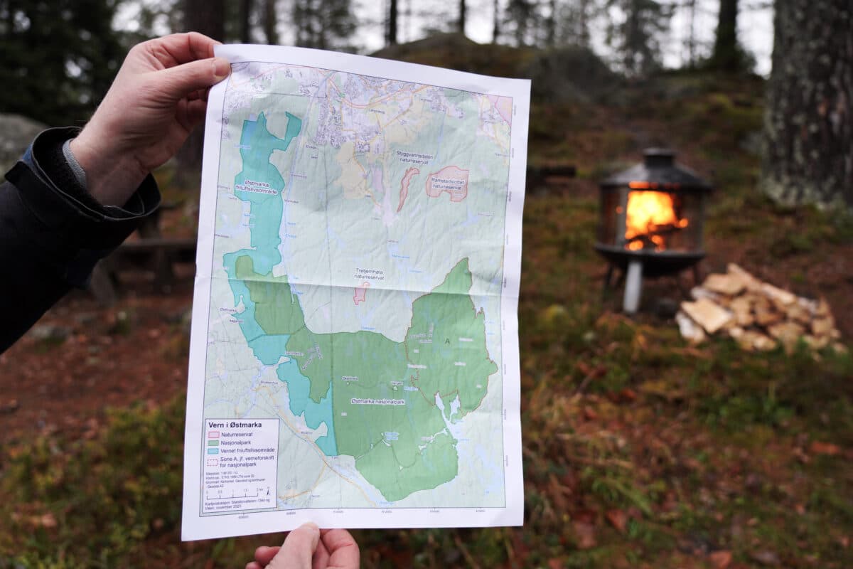 En person holder opp et kart foran et bål.