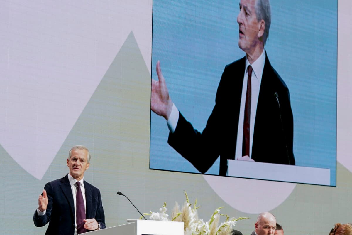 En mann holder en tale foran en stor skjerm.