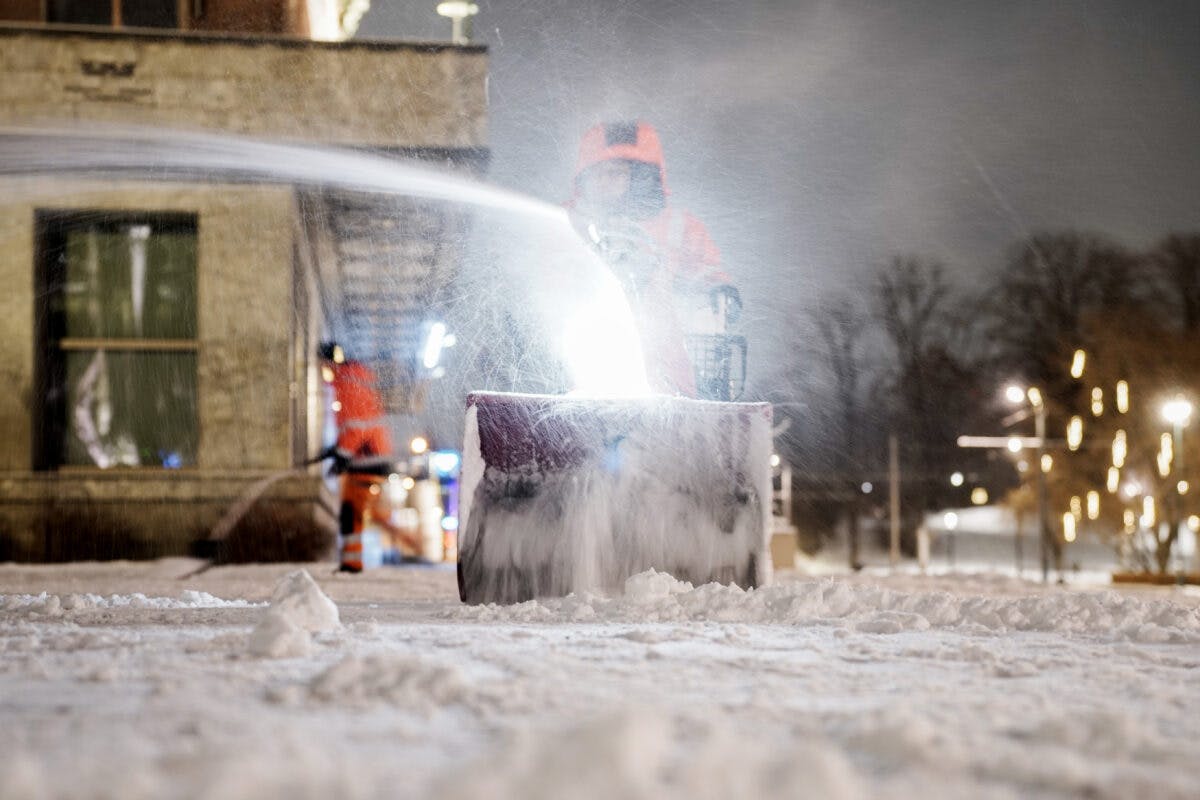 En mann som rydder snø med snøfreser utenfor Rådhuset i Oslo.