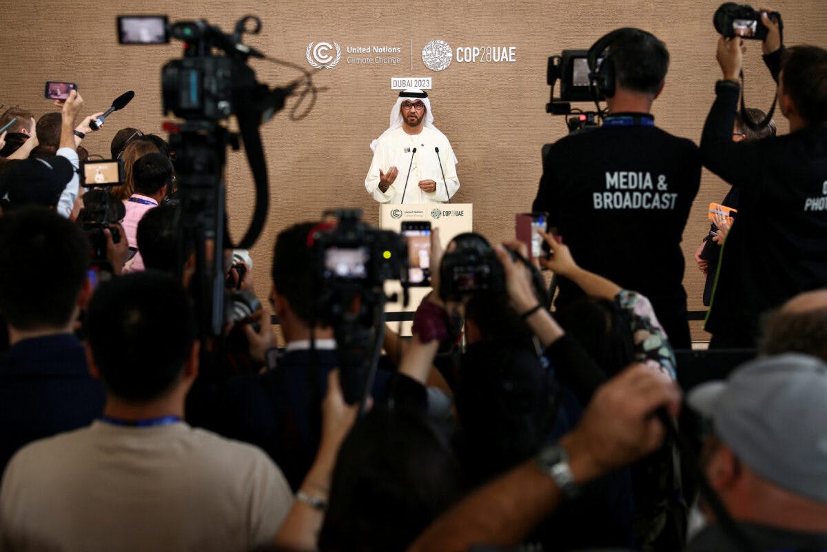 En mann står foran en gruppe mediefolk.