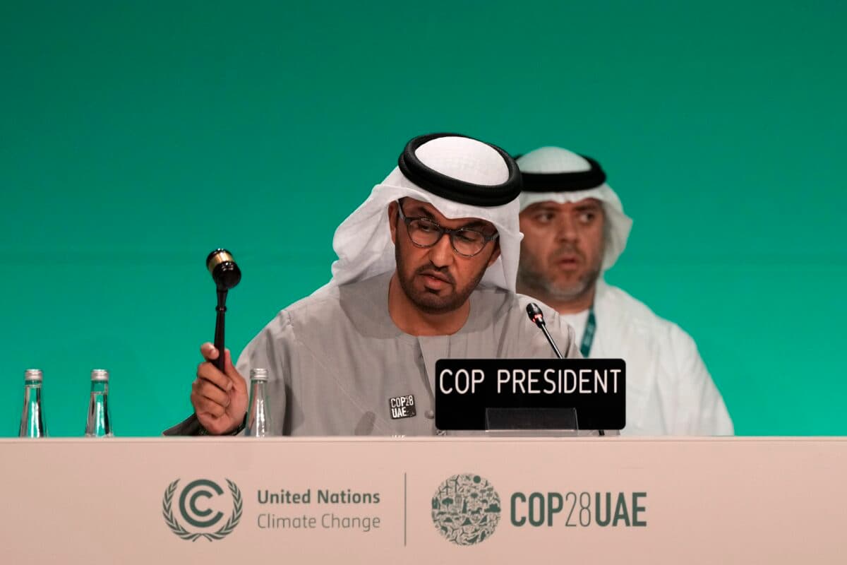 To menn taler på en konferanse foran et podium.