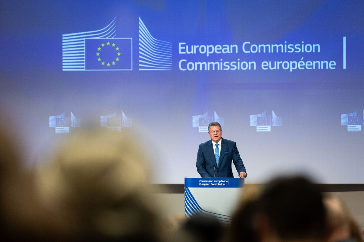 EU-kommissær står på et podium foran en skjerm.