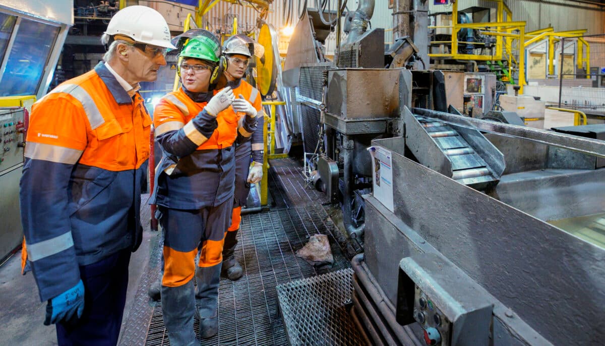 En gruppe arbeidere som står foran en maskin.