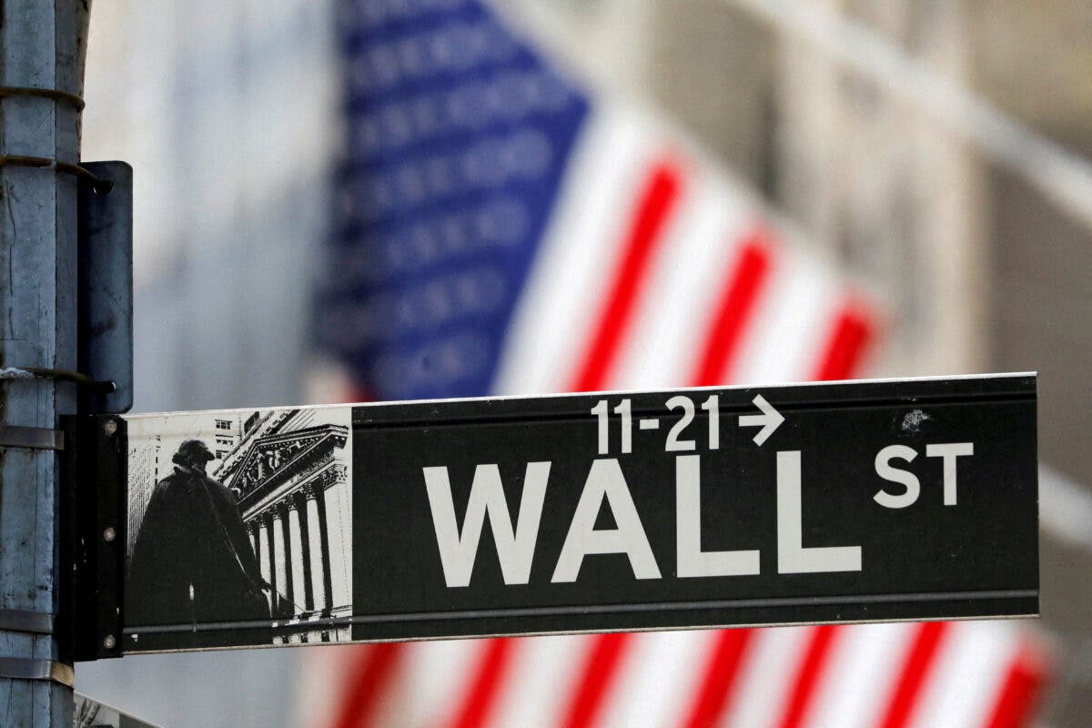 Et Wall Street-skilt med et amerikansk flagg i bakgrunnen.