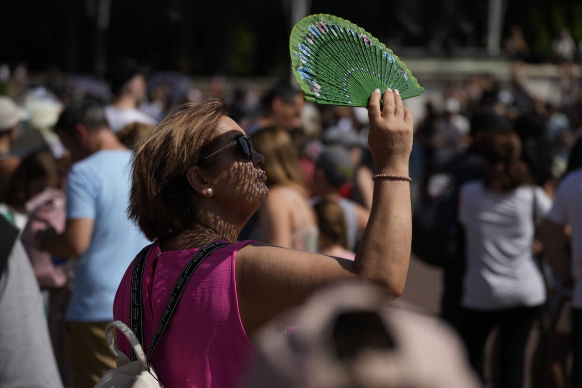 En kvinne i solbriller vifter seg i en overfylt utendørs setting.