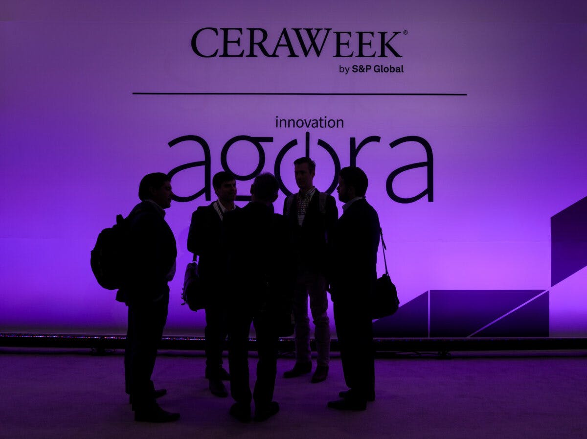 Deltakere i silhuett samtaler foran det opplyste «ceraweek agora by s&p global»-skiltet.