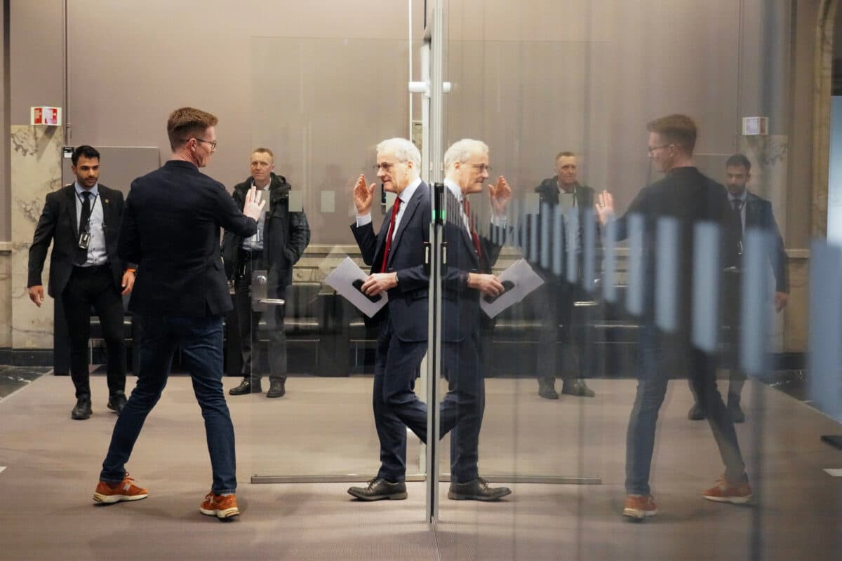 Forretningsfolk som deltar i en samtale gjennom en glassdør, med andre i bakgrunnen.