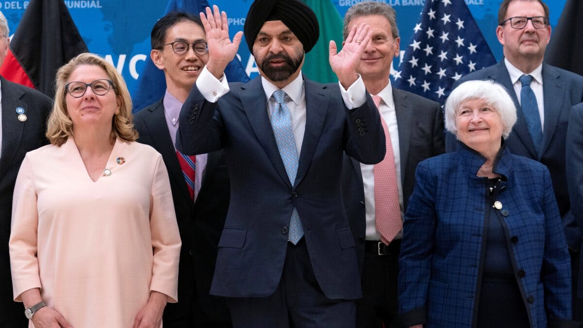 Gruppe av forskjellige bedriftsledere og politikere, smilende under en foto-op på et arrangement, med flagg i bakgrunnen.