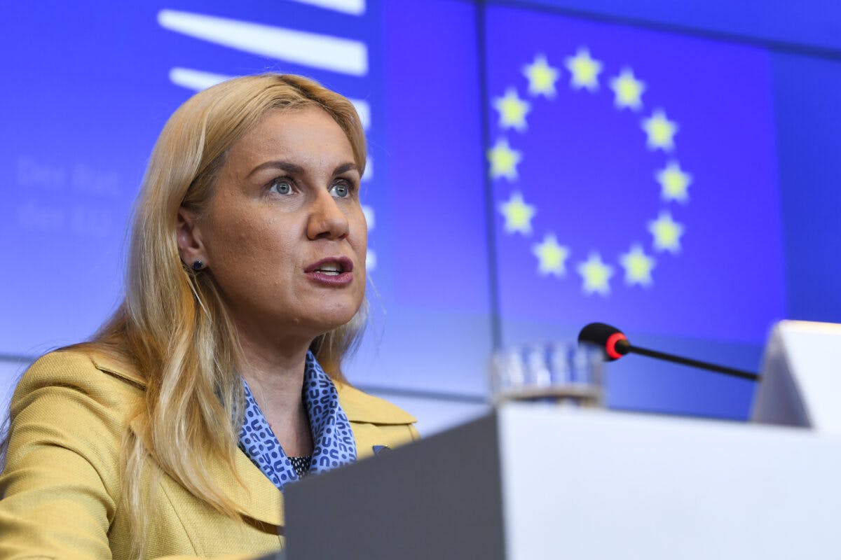 En kvinne taler ved et podium med EU-flagget i bakgrunnen.