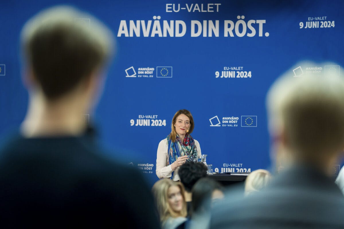 Kvinne taler ved et podium med "eu-valet"-bannere, henvender seg til et publikum, dato merket som "9 juni 2024" synlig.