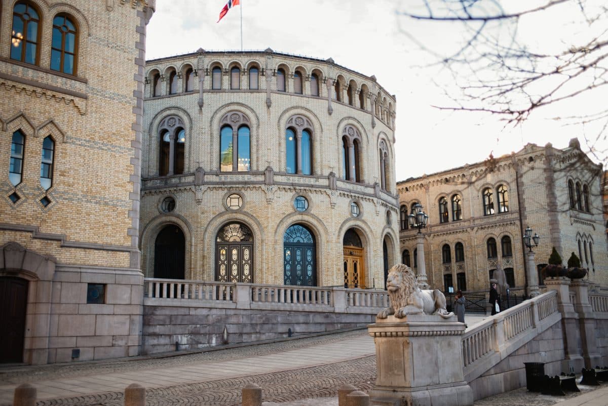 En historisk, rund mursteinsbygning med buede vinduer, flankert av en løvestatue på en steintrapp; et flagg vaier på toppen av bygningen.