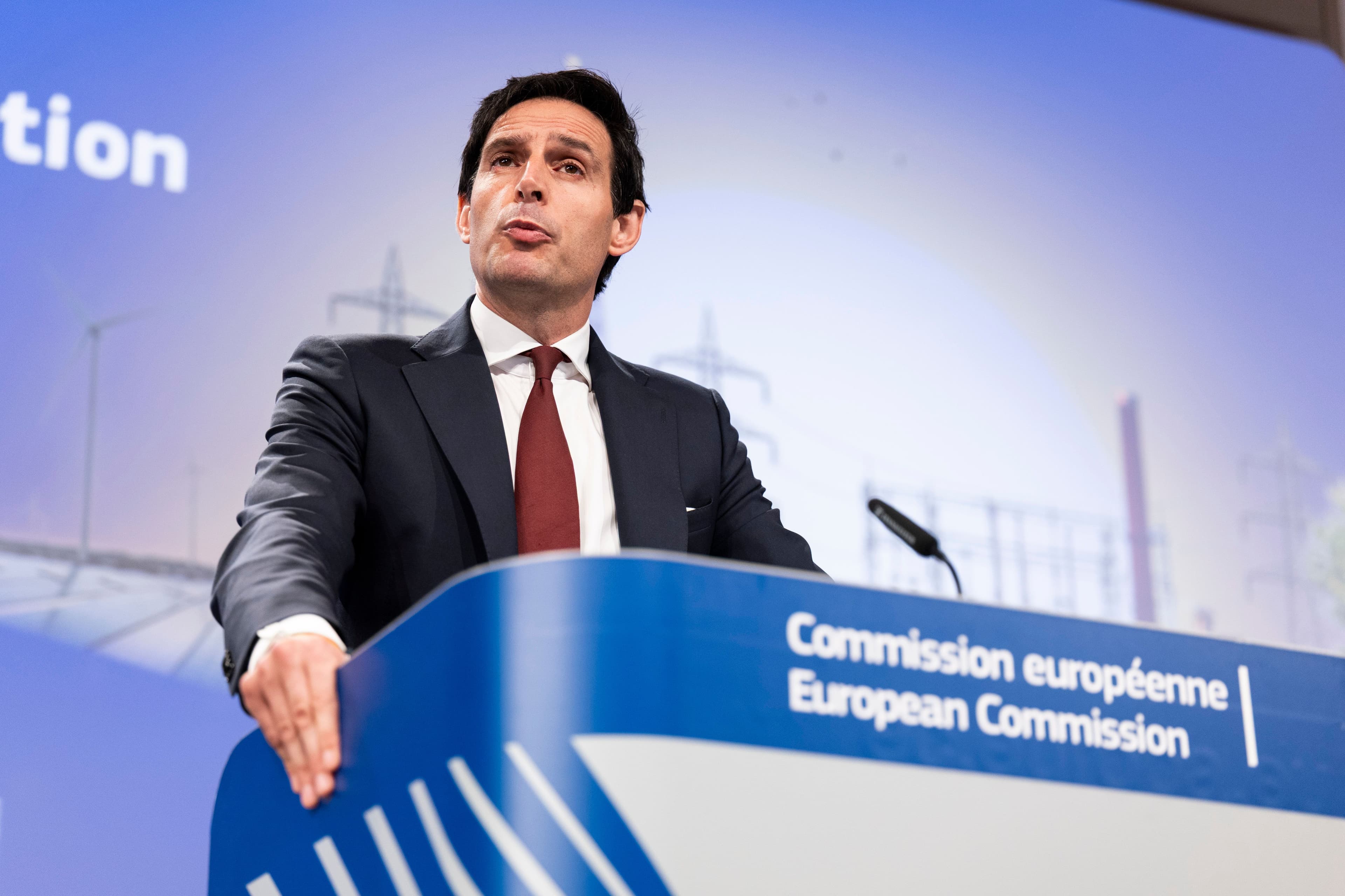 En mann taler på en pressekonferanse i EU-kommisjonen, med grafikk om energiinfrastruktur i bakgrunnen.