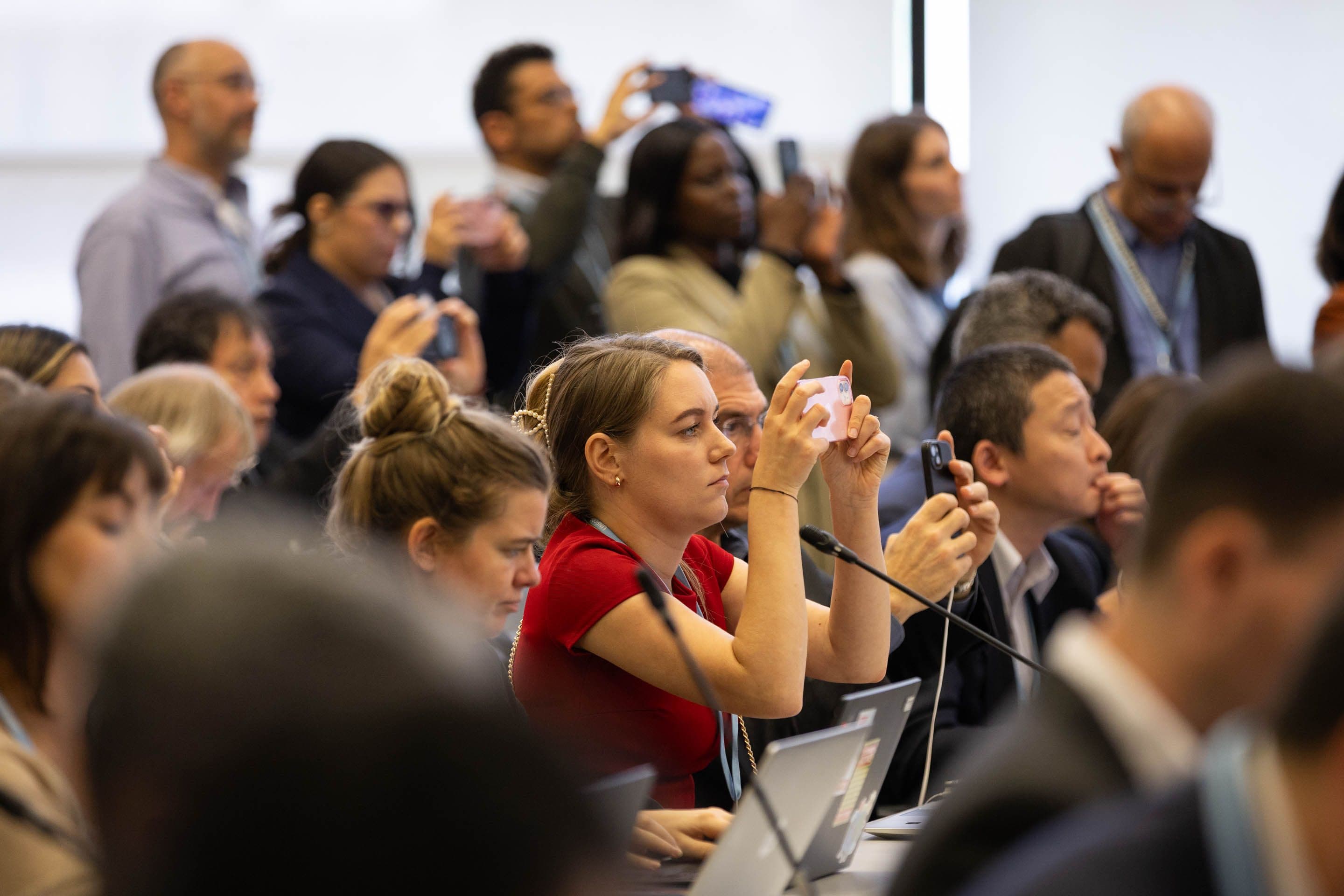 Konferansedeltakere som filmer med smarttelefoner.