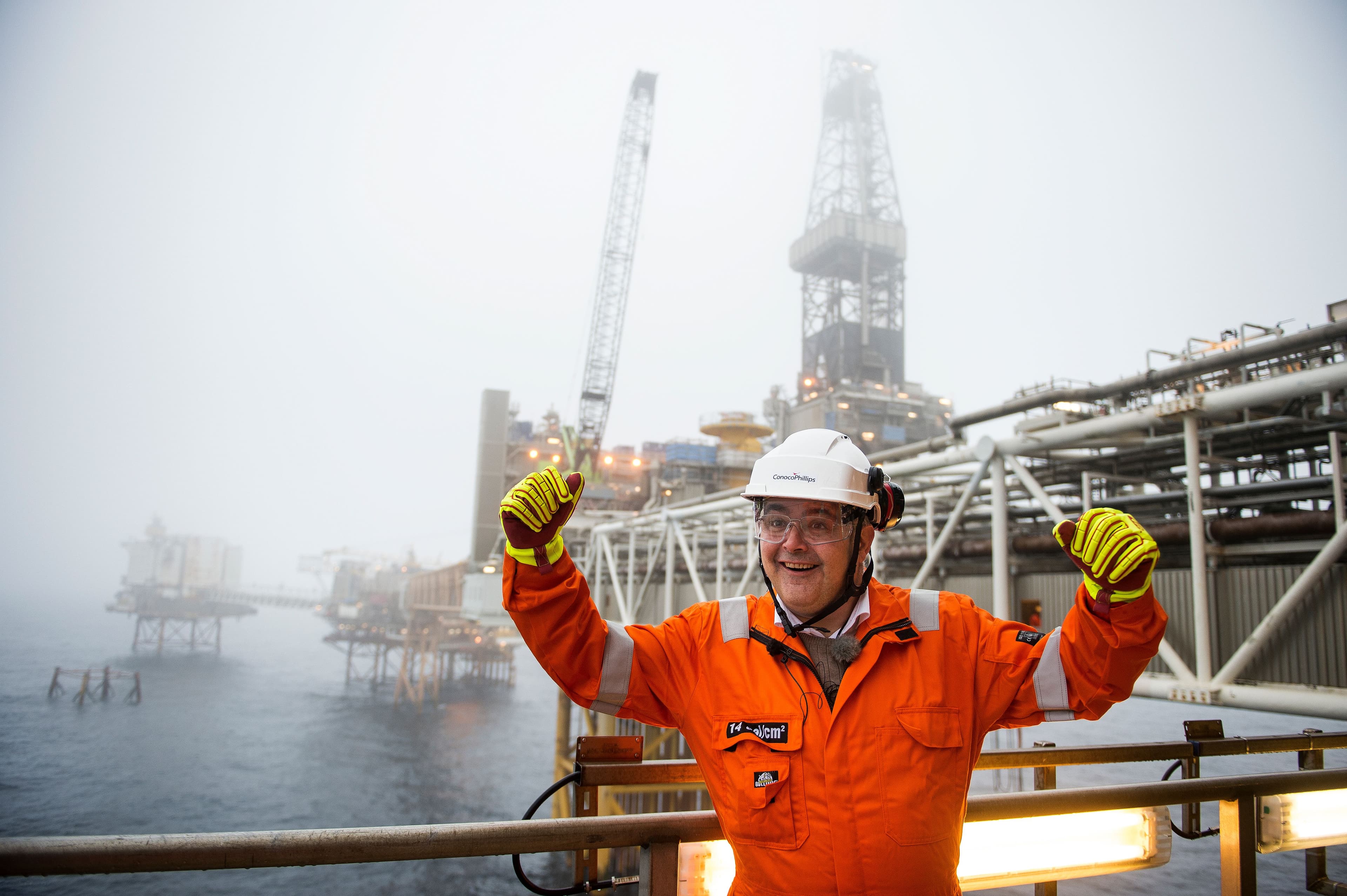Man in safety gear celebrating on a foggy offshore oil rig.