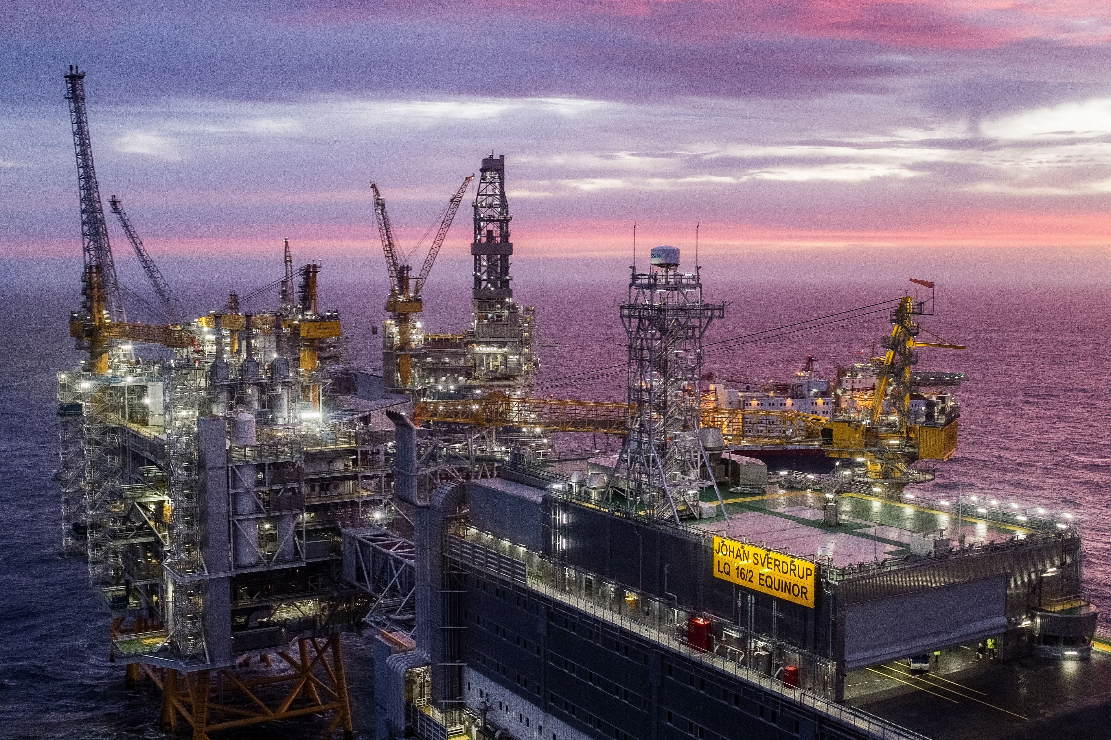 Den opplyste Johan Sverdrup-plattformen til havs under en skumringshimmel med rosa og lilla sjatteringer.