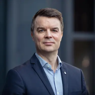 Portrettfoto av en mann i blå dressjakke og stripete skjorte.